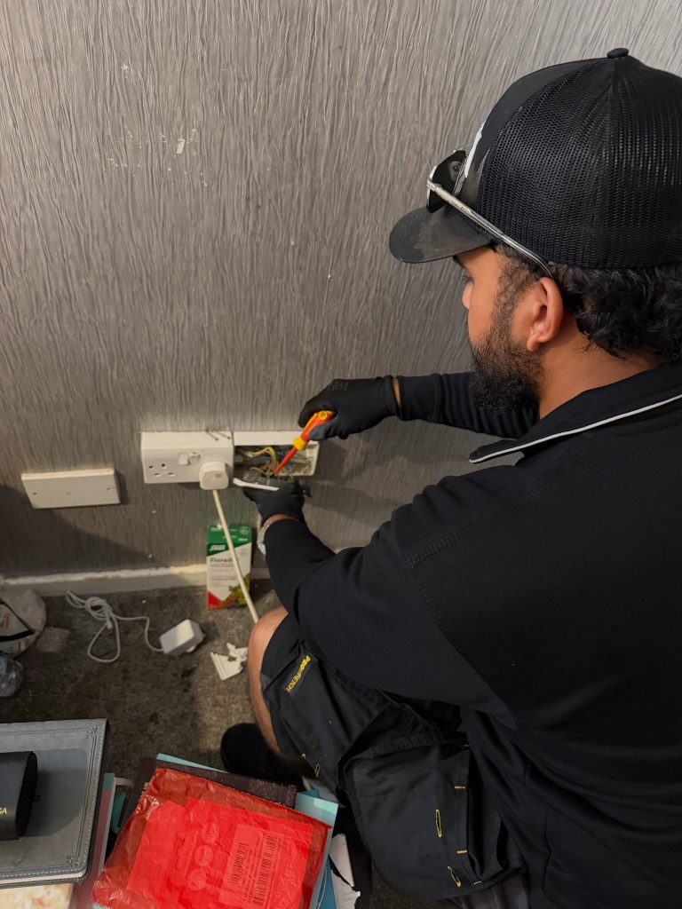 Electrician working on a wall socket with the faceplate removed