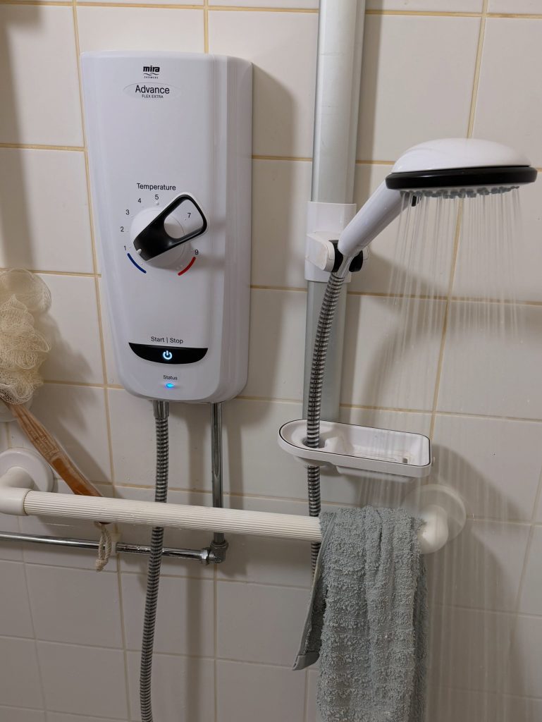 Electric shower installed and running in a tiled bathroom