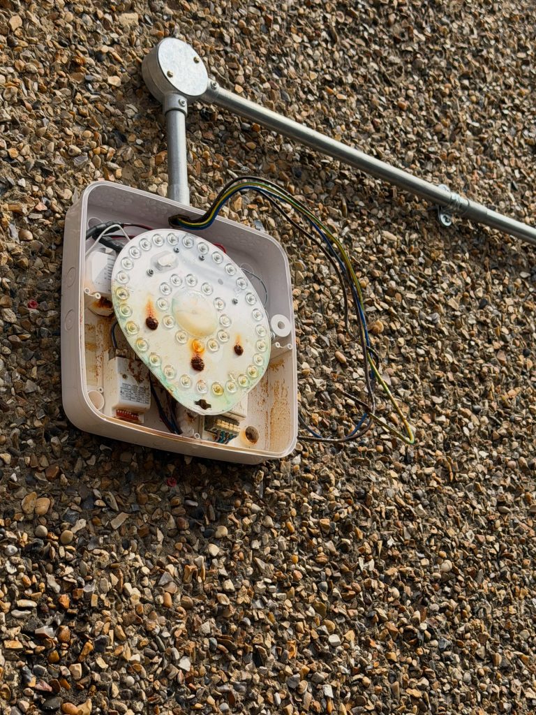Corroded outdoor bulkhead light opened up, rusted inside